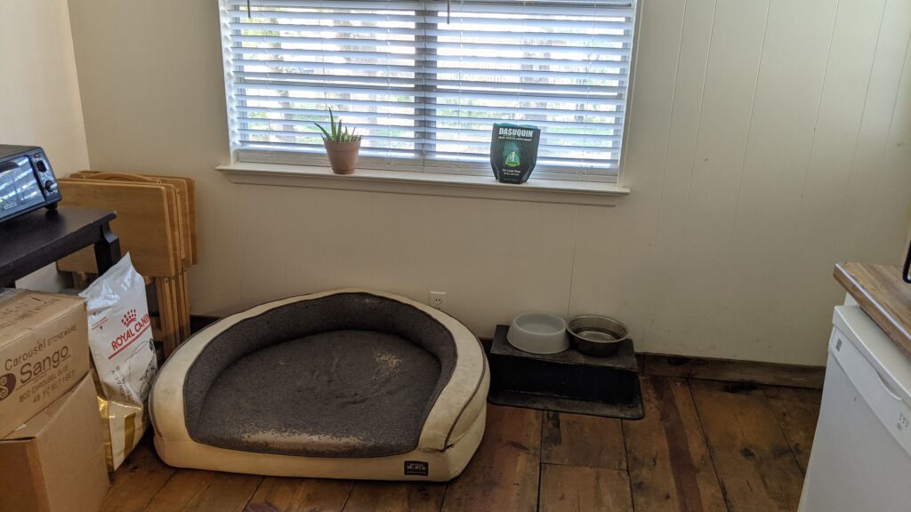 Picture of Kora's bed and food bowls by the back door.